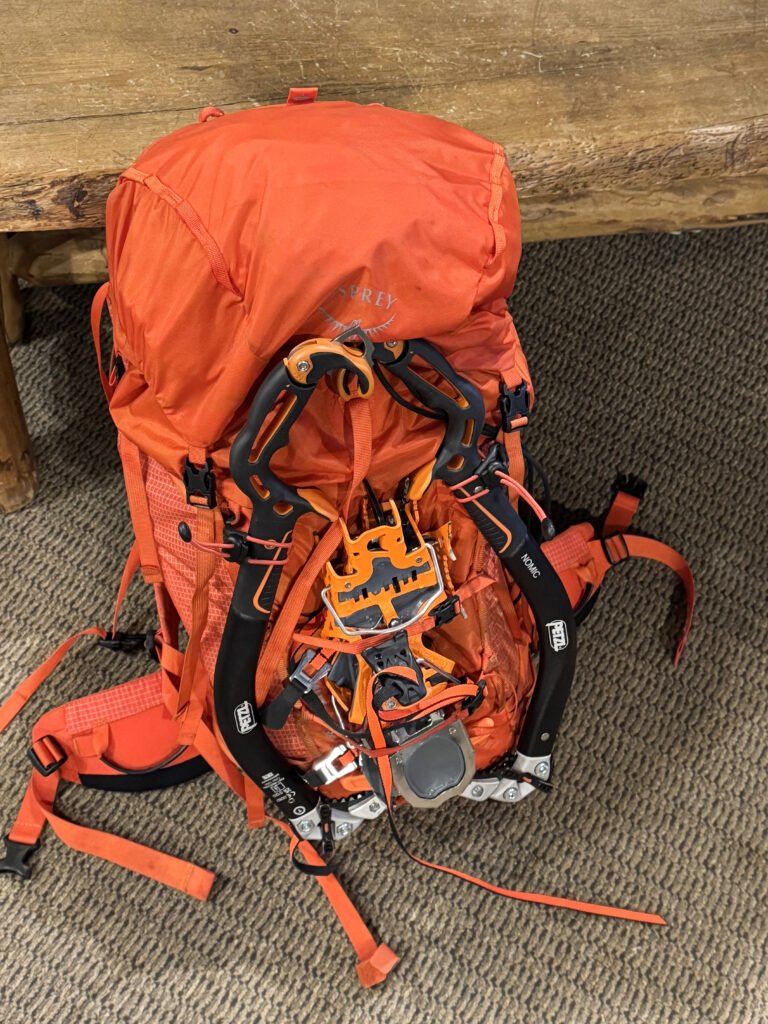 An orange backpack with crampons and ice tools.