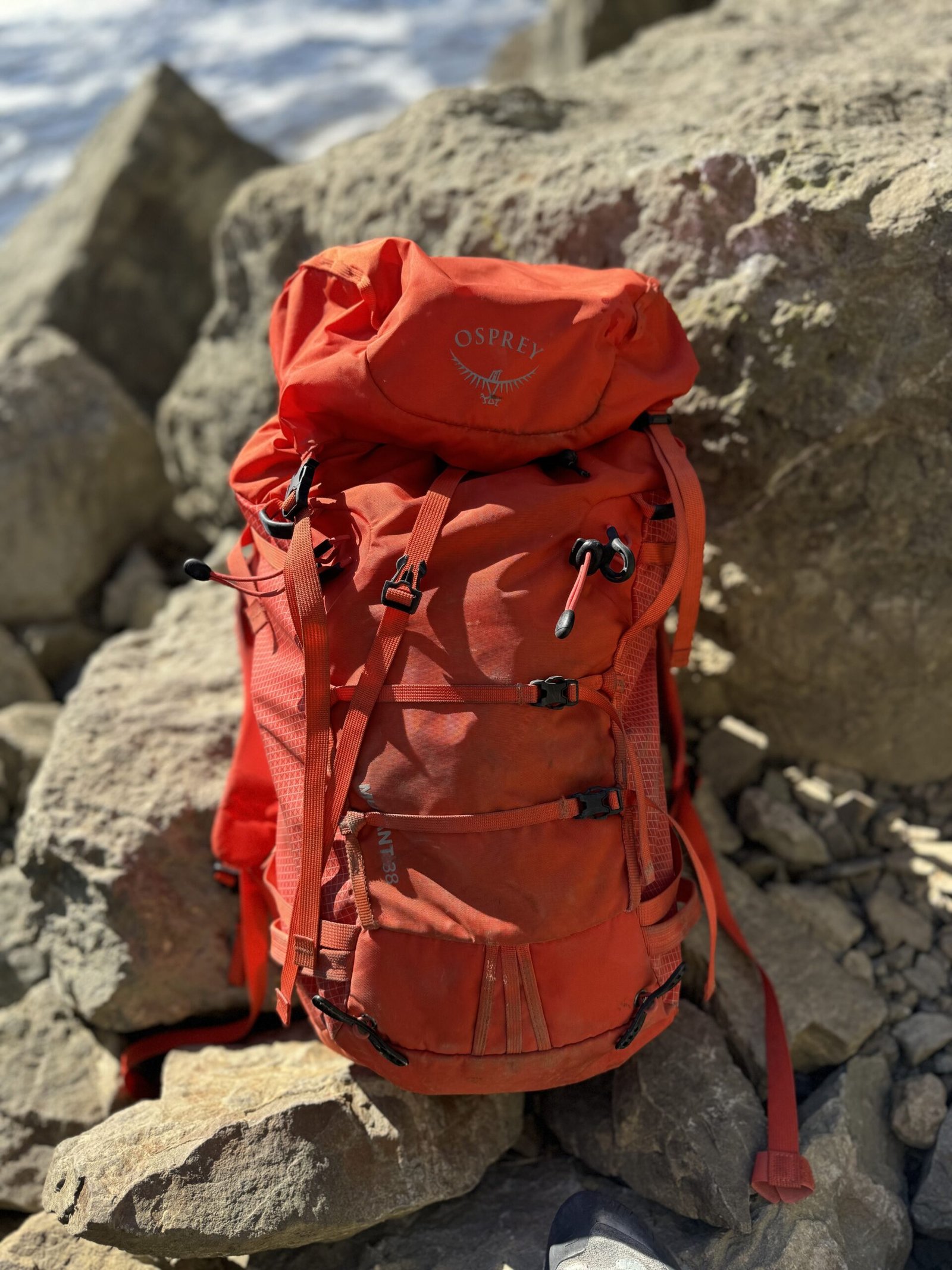 An orange backpack sitting on rocks