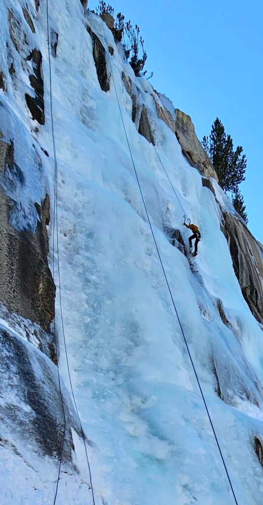 An ice climber high up a wall of ice.
