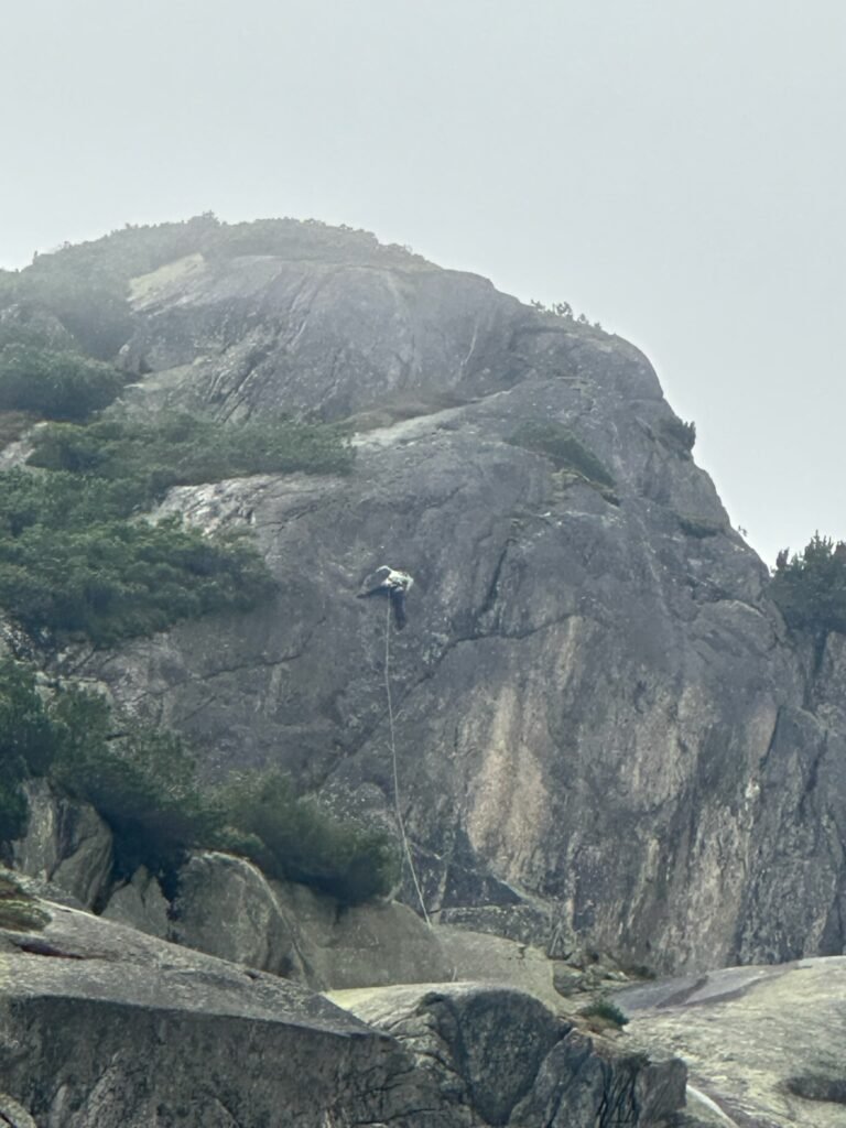 A rock climber on a foggy rock.